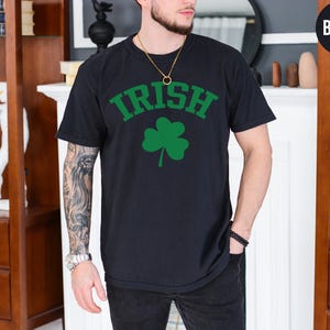 a man wearing a black shirt with a shamrock on it