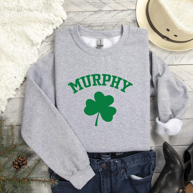 a casual outfit consisting of a gray sweatshirt with the word "MURPHY" printed on it, a pair of jeans, and a hat.