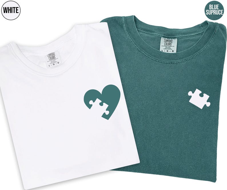 two t-shirts, one white and one green, with a heart-shaped puzzle piece design on the front.