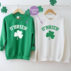 two green and white sweatshirts hanging on a clothes line