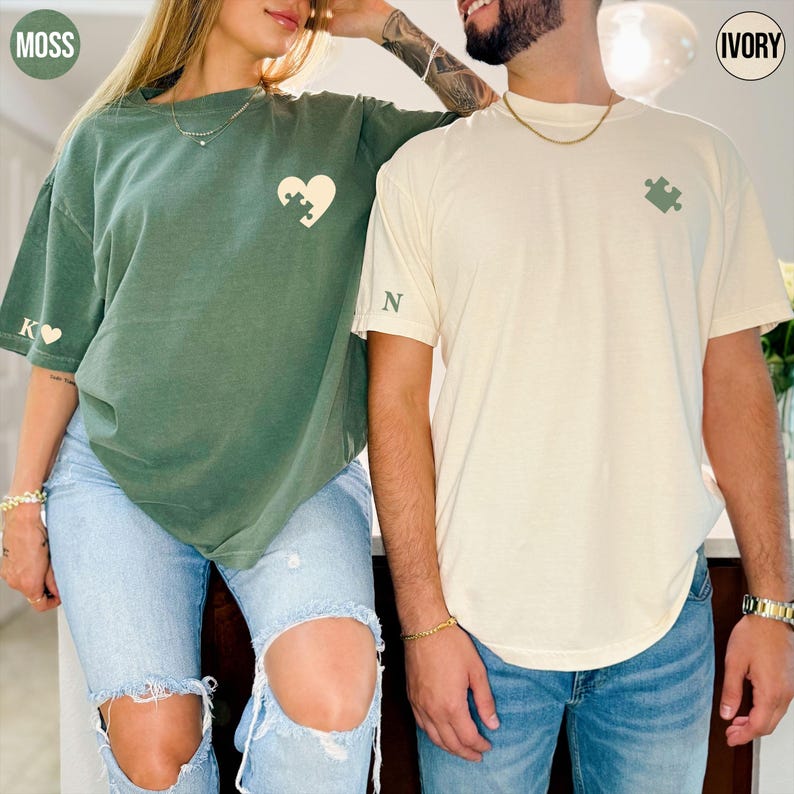 A man and a woman standing close together, both wearing t-shirts with a heart design.