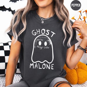 A person wearing a black t-shirt with a graphic of a ghost and the text "GHOST MALONE" printed on it.
