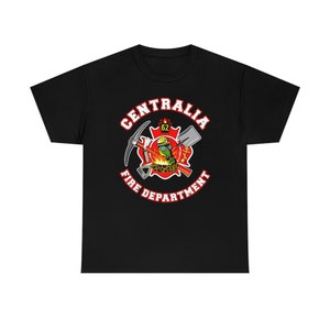 Könnte beinhalten: Schwarzes T-Shirt mit einem roten und weißen Logo, auf dem "Centralia Fire Department" steht, mit einem Feuerwehrhelm, einer Spitzhacke, einer Schaufel und anderen Werkzeugen in der Mitte.