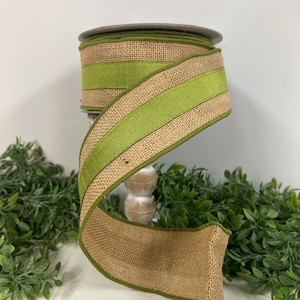 May include: A roll of burlap ribbon with green velvet stripes. The ribbon is 2.5 inches wide and is perfect for crafting and decorating.