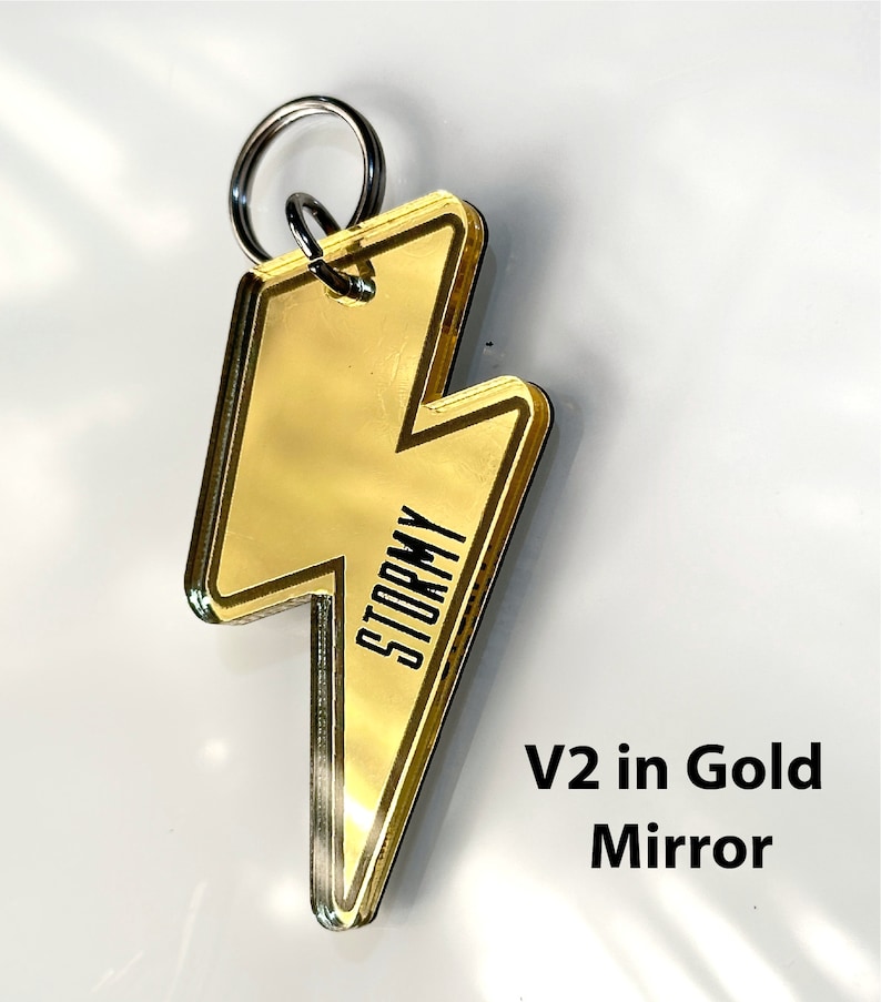 May include: Gold lightning bolt keychain with the word "Stormy" printed on it. V2 in Gold Mirror.