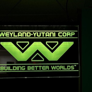 May include: A black and green sign with the text "Weyland-Yutani Corp." and a stylised "W" logo. The text "Building Better Worlds" is below the logo.