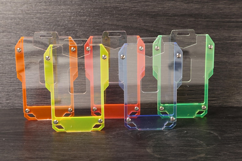 May include: A set of five rectangular badge holders made of transparent acrylic with colored borders in orange, yellow, red, blue, and green. Each holder features a top slot for a lanyard and small metal screws securing the clear front panel.