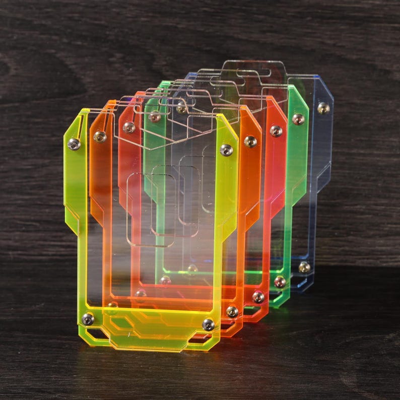 May include: A set of four rectangular, translucent acrylic card holders in yellow, orange, green, and blue. Each holder features a geometric, layered frame design secured with small silver-toned metal screws at the corners and sides.