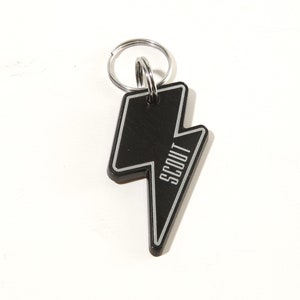 May include: Black metal keychain shaped like a lightning bolt with the word "SCOUT" written vertically on the keychain.