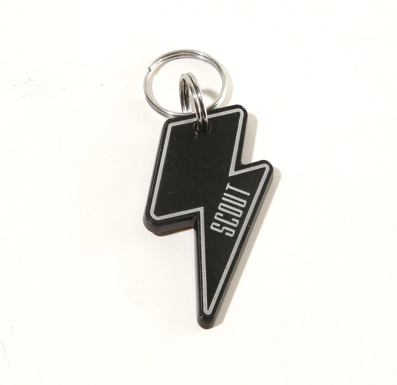 May include: Black metal keychain shaped like a lightning bolt with the word "SCOUT" written vertically on the keychain.