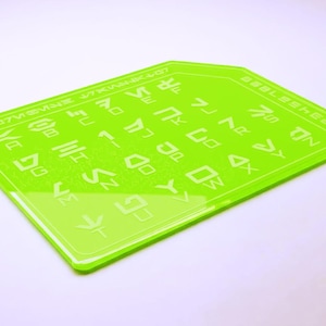 May include: A bright green rectangular sheet with etched white symbols and text. The sheet has rounded corners and a glossy finish. The text includes the words "K07MSNE" and "B00LSHEET".