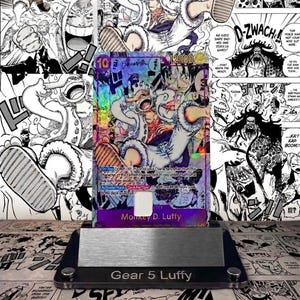 Może przedstawiać: Holograficzna karta kolekcjonerska przedstawiająca Monkey D. Luffy w formie Gear 5, o mocy 12000. Karta jest prezentowana na stojaku z napisem "Gear 5 Luffy". Tło to kolaż paneli z mangi.