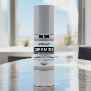 Puede incluir: Un frasco blanco de suero de barrera de ceramida BeauWorld Skin Soo. El frasco tiene una tapa plateada y una etiqueta que dice "Restaurar. Proteger. Transformar. Construir y reforzar la barrera natural de la piel. Todos los tipos de piel. Sin parabenos ni sulfatos. Hecho en EE. UU. 30 ml."