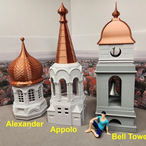 May include: Three miniature white and copper-colored buildings with a copper-colored dome, a copper-colored spire, and a gray bell tower. The buildings are labeled "Alexander", "Appolo", and "Bell Tower".
