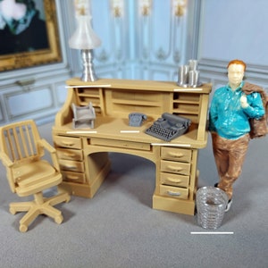 May include: A miniature wooden desk with a roll top, six drawers, and a typewriter on the surface. A miniature chair, a lamp, and a small trash can are also included. The desk is painted in a light brown color.