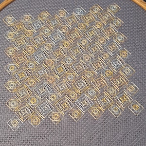 May include: A needlepoint embroidery project featuring a repeating geometric pattern of interlocking squares. The design is stitched with metallic gold, silver, and copper threads on a dark grey fabric background, creating a textured grid effect.