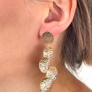 May include: Gold tone dangle earrings with four textured round discs.