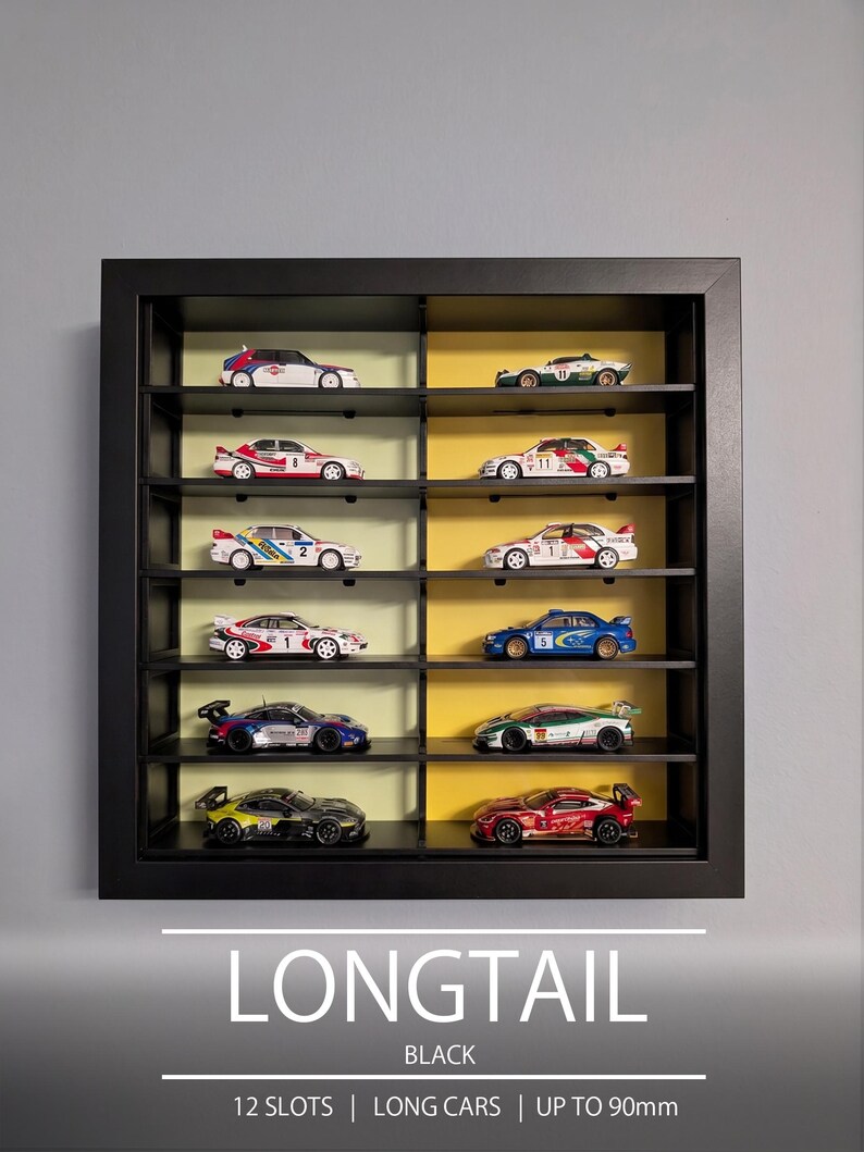 Pu&ograve; includere: Una vetrinetta da parete nera con 12 scomparti per modellini di auto. L'interno presenta pannelli posteriori che si alternano tra verde chiaro e giallo. Il testo in basso recita: LONGTAIL BLACK 12 SLOTS | LONG CARS | UP TO 90mm.