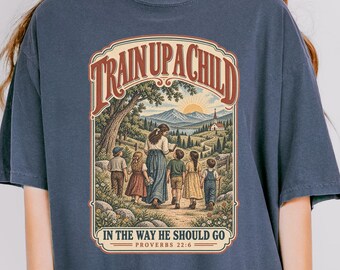 May include: A charcoal gray short-sleeve t-shirt featuring a graphic print of a person walking with four children on a path toward a church. The text reads TRAIN UP A CHILD IN THE WAY HE SHOULD GO PROVERBS 22:6 in a decorative arched frame.