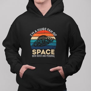 May include: A black hoodie with a retro-style graphic of a UFO and the text "I'm a huge fan of space, both outer and personal."