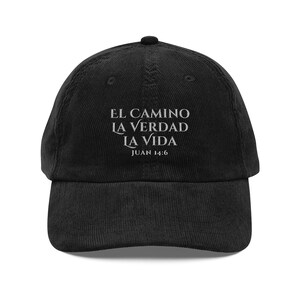May include: Black corduroy baseball cap with white embroidered text that reads "El Camino La Verdad La Vida Juan 14:6".