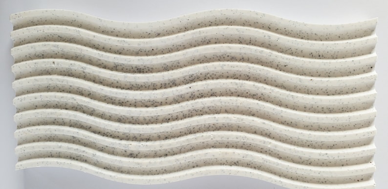 May include: A white, wavy, textured surface with a speckled pattern. The surface is made of a material that resembles concrete or plaster.