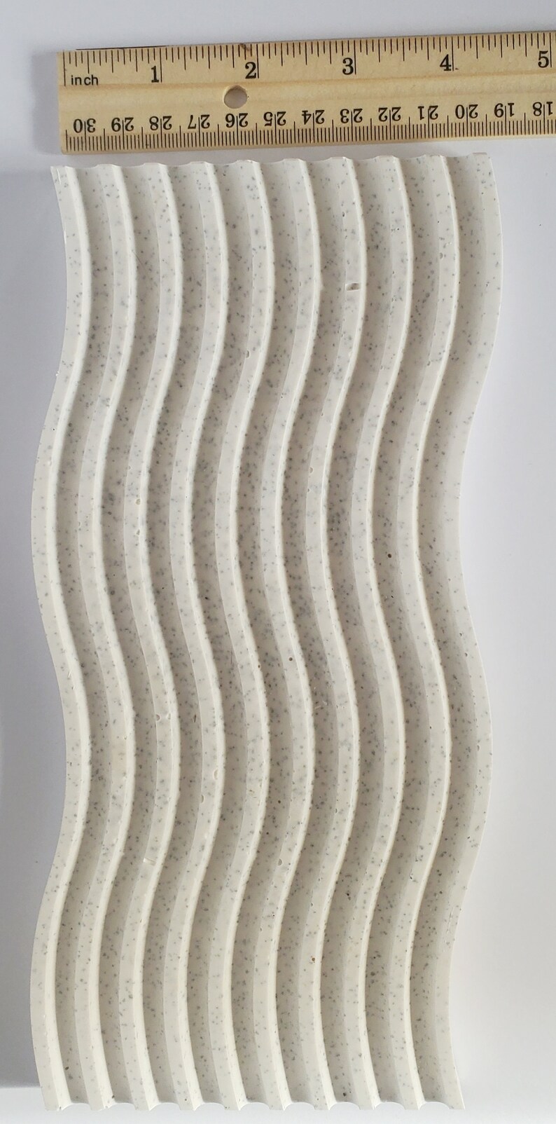 May include: A white, textured, wavy surface with a speckled pattern. The surface is approximately 5 inches wide and 18 inches long.