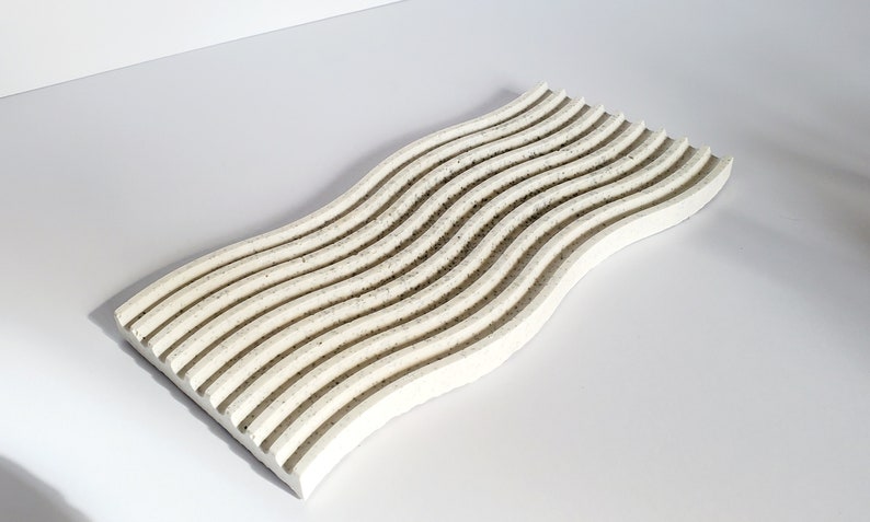 May include: White wavy tray with a textured surface. The tray is made of concrete and has a modern design.
