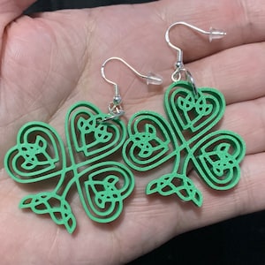 May include: A pair of green clover earrings with a silver hook. The clover design is intricate and detailed, with multiple layers of hearts.