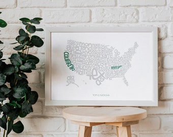 Könnte beinhalten: Ein gerahmter Druck einer Karte der Vereinigten Staaten von Amerika, die aus Wörtern besteht. Die Wörter sind grau, außer "California" und "Texas", die grün sind. Der Druck ist auf weißem Hintergrund und hat einen weißen Rahmen. Der Druck steht auf einem Holzhocker vor einer weißen Backsteinwand.