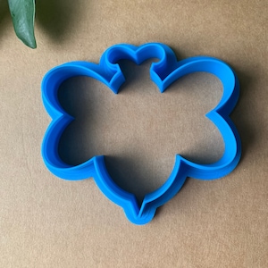 May include: Blue plastic cookie cutter shaped like a bee. The cutter has a detailed design with a rounded body and wings.