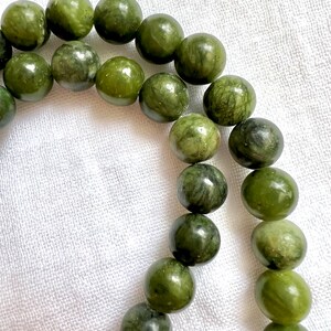 Puede incluir: Un collar de cuentas de jade verde, cada cuenta es redonda y tiene un patr&oacute;n de m&aacute;rmol.