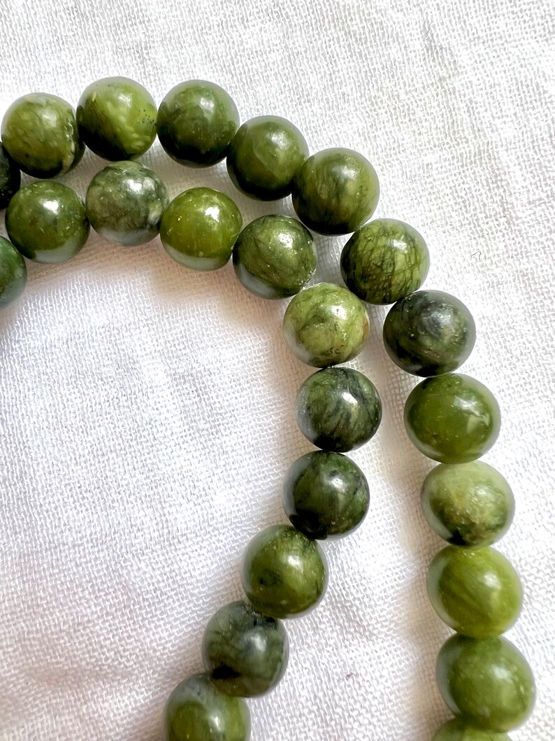 Puede incluir: Un collar de cuentas de jade verde, cada cuenta es redonda y tiene un patr&oacute;n de m&aacute;rmol.