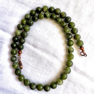 Puede incluir: Un collar de jade verde con cierres de cobre. El collar est&aacute; hecho de cuentas redondas y mide aproximadamente 45 cm de largo.
