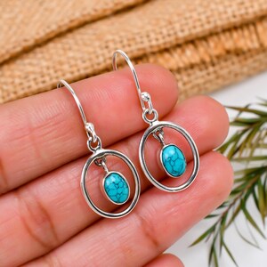 May include: A pair of silver dangle earrings with turquoise stones set in a circle.