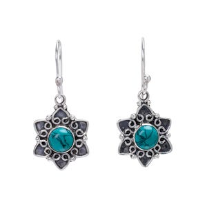 May include: A pair of silver earrings with a flower-shaped design. Each earring features a turquoise-colored stone in the center, surrounded by a detailed, dark silver floral pattern. The earrings have a hook closure.