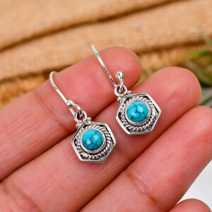 May include: A pair of silver dangle earrings with turquoise gemstones set in a hexagonal frame.