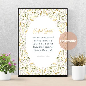 May include: A framed print with the quote "Kindred Spirits" in gold script, surrounded by a floral border. The quote is from Anne of Green Gables. A small, round "Printable" sticker is in the corner.