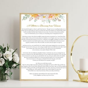 Op de afbeelding: Een ingelijste print met de tekst "A Mother's Blessing from Heaven" en een bloemenontwerp. De tekst is een oprechte boodschap van een moeder aan haar dochter, met een goudkleurige lijst.