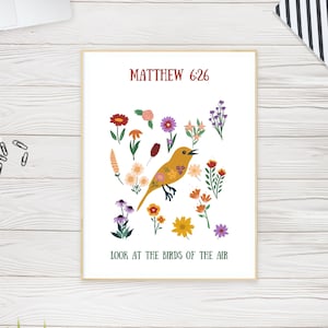 May include: A framed print with a yellow bird illustration, adorned with flowers, and various colorful blooms. The text reads "Matthew 6:26" and "Look at the birds of the air". The artwork is set against a white background, with a wooden frame.
