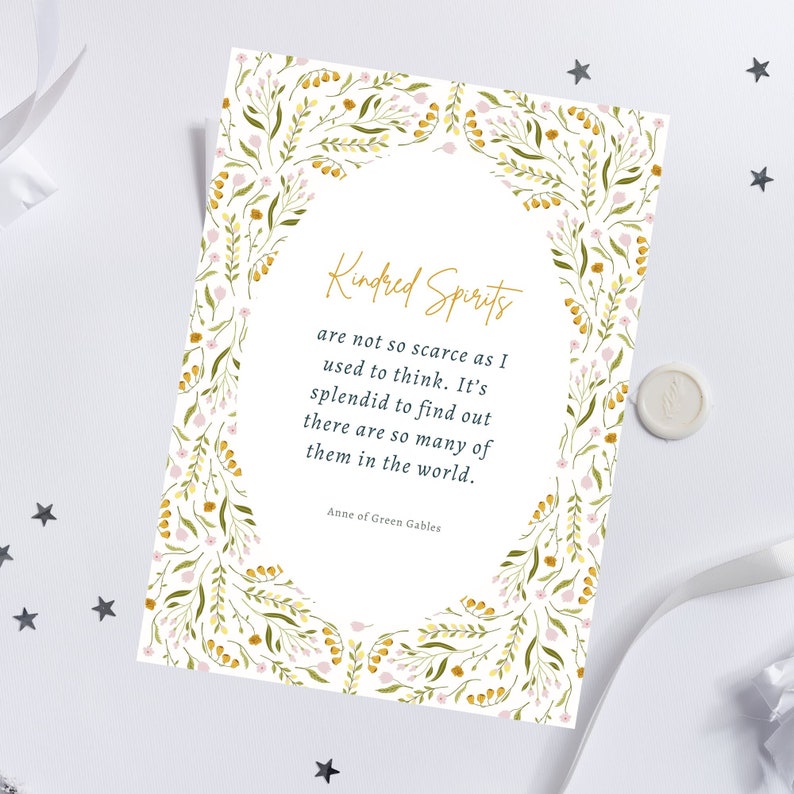 May include: A white card with the text "Kindred Spirits" in gold script, surrounded by a floral border of green leaves and pink and yellow flowers. The quote is from Anne of Green Gables.
