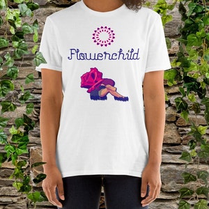May include: White t-shirt with a pink flower design and the text "Flowerchild" in purple. A cartoon illustration of a person lying under a large pink rose.