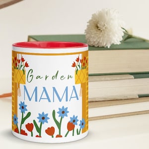 May include: White ceramic mug with a red rim. The mug has a yellow and orange border with a design of hanging flower pots and flowers. The text "Garden MAMA" is printed in blue and yellow letters.