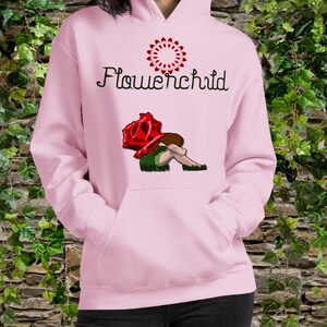Könnte beinhalten: Rosafarbener Hoodie mit einem Flower-Child-Motiv. Das Motiv zeigt eine Person, die unter einer großen roten Rose sitzt.