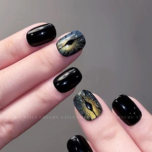 Peut inclure: Vernis à ongles noir avec un design de paillettes dorées et bleues sur un ongle.