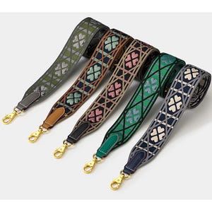 May include: Five patterned bag straps with gold-coloured clasps. Each strap displays a different colour scheme, including green, brown, pink, green, and blue, with a repeating clover design. The straps are woven and have leather accents.