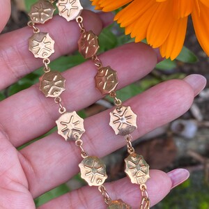 May include: Gold bracelet with a chain and round charms featuring a starburst design.