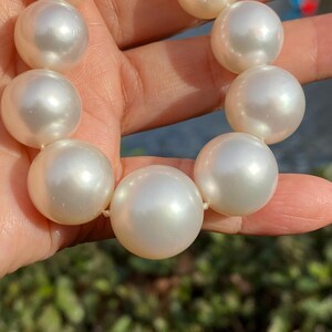 Pode incluir: Um colar de p&eacute;rolas grandes, brancas e cremosas. As p&eacute;rolas s&atilde;o esf&eacute;ricas e t&ecirc;m um brilho brilhante. As p&eacute;rolas s&atilde;o enfiadas, possivelmente formando um colar ou uma pulseira.
