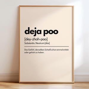 May include: A framed print with the words "deja poo" in bold black letters. Below the title is the phonetic pronunciation and the German word for noun. The definition of the phrase is written in German below.