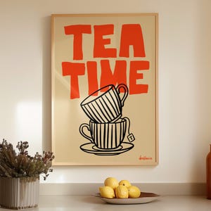 Könnte beinhalten: Ein rechteckiger Wandkunstdruck in einem hellen Holzrahmen mit dem fetten orangefarbenen Text TEA TIME über einer schwarz-weißen Strichzeichnung von zwei gestapelten gestreiften Teetassen auf einer Untertasse mit einem Teebeutelanhänger.